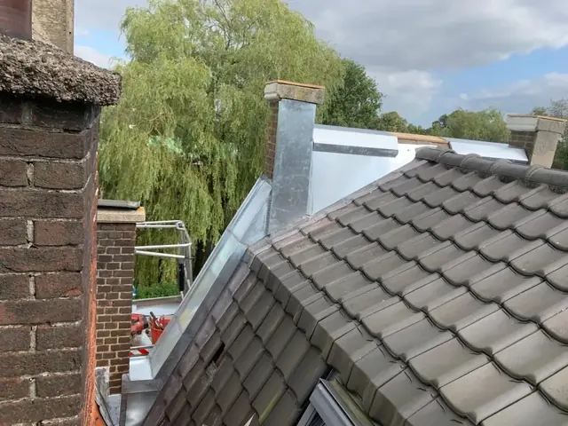 Schoorstenen op een pannendak — Overzicht van gemetselde schoorstenen en aansluitingen op grijze dakpannen.